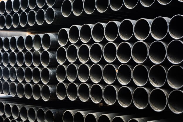 Tubos de aço carbono e galvanizado empilhados, utilizados na construção civil e na indústria em aplicações estruturais e condução de fluidos.